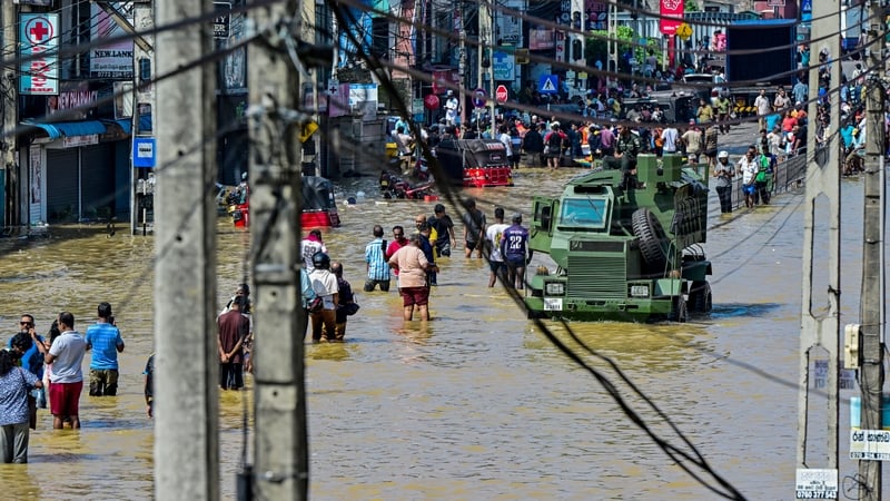 Damaged wires dangle from electric poles as an army truck wades through a flooded street after heavy rainfall in Wellampitiya on the outskirts of Colombo, Sri Lanka