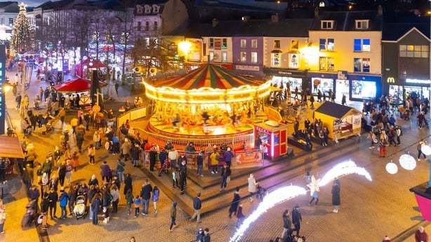 Bright lights and a carosuel as people walk around it