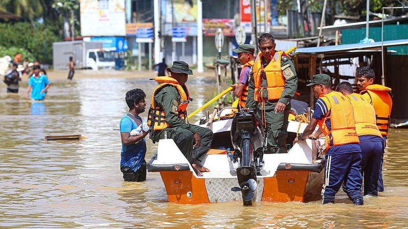 A group of Sri Lankan Army soldiers travel by boat through floodwaters to deliver food packages to shelters after heavy rains