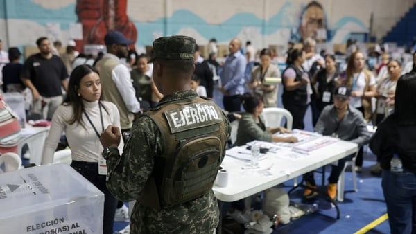 A security guard stands stands guard as people vote