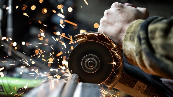 Metalworker operating an angle grinder actively cutting on a metal surface, emitting dynamic sparks. Depicts craftsmanship, industrial labor, and the creative sparks of manufacturing processes under precise control.
