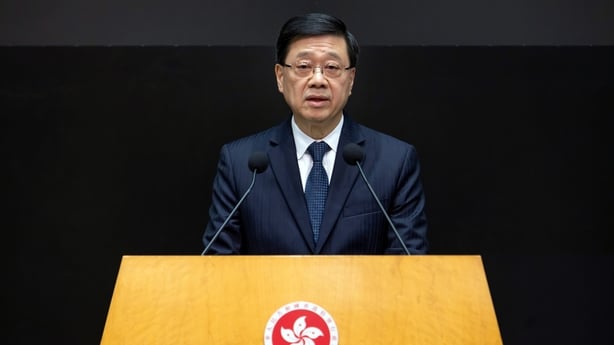Hong Kong's chief executive John Lee stands behind a podium during a news conference.