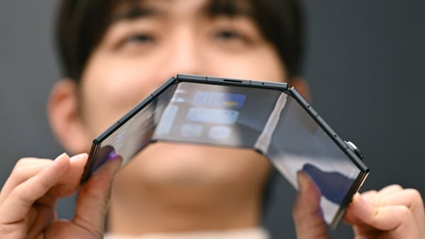 A promoter shows a Samsung Galaxy Z TriFold smartphone during a launch event at a Samsung store in Seoul on December 2, 2025. Samsung Electronics unveiled its first tri-fold phone on December 2, as the conglomerate rushes to show it can keep pace with riv