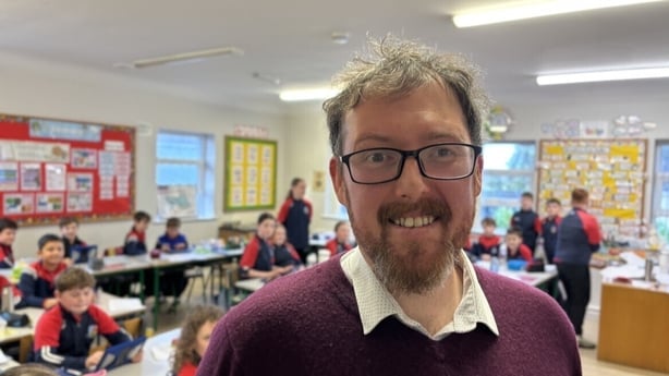 Eoin O Donnchadha stands in a classroom.
