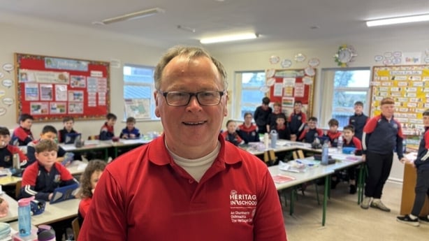 Martin Curely stands in a classroom.