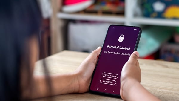 A young Asian girl holding a locked smartphone with parental control notification on the screen