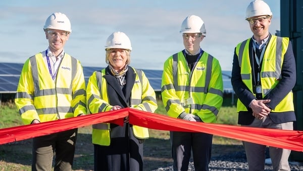 Three men and a woman in high-vis jackets cutting a red ribbon