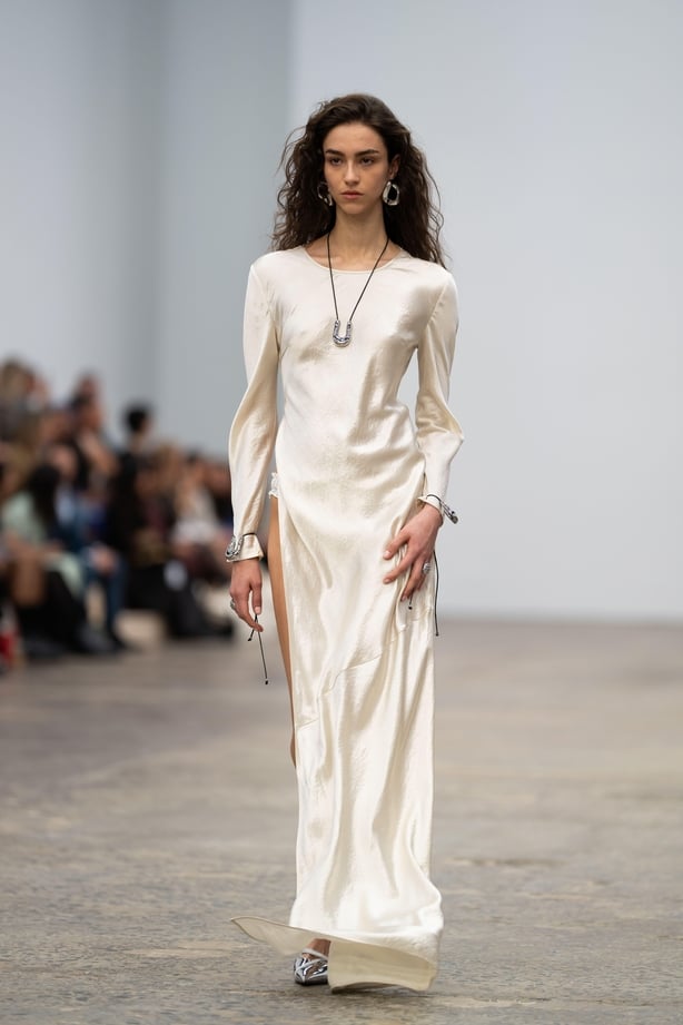 Model walking on a runway in a long white dress