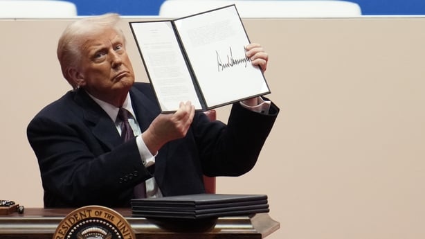 Donald Trump holds up an executive order after signing it during an indoor inauguration parade 
