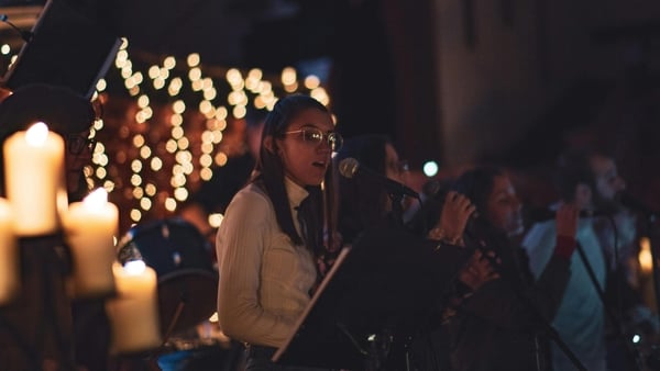 Girl singing with a choir in a candlelit setting