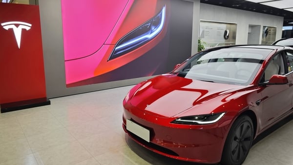 A red Tesla model 3 car in a showroom