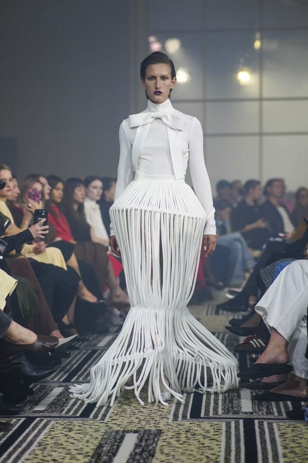 A model wearing a white gown on the runway