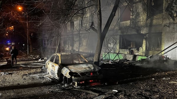A man stands next to a burnt out car in the courtyard of a damaged residential building following an air attack in Zaporizhzhia