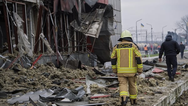 Ukrainian rescuers walk past a heavily damaged train station building in the town of Fastiv, Kyiv
