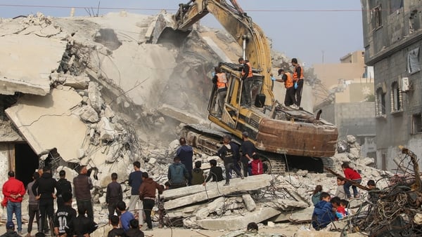 Civil Defence personnel use an excavator to search for the remains of victims in the rubble of a destroyed building in the Bureij refugee camp, in the central Gaza Strip