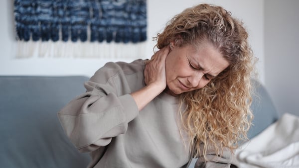 Tired middle aged woman touching her neck with hand, suffering from neck pain. Midlife health