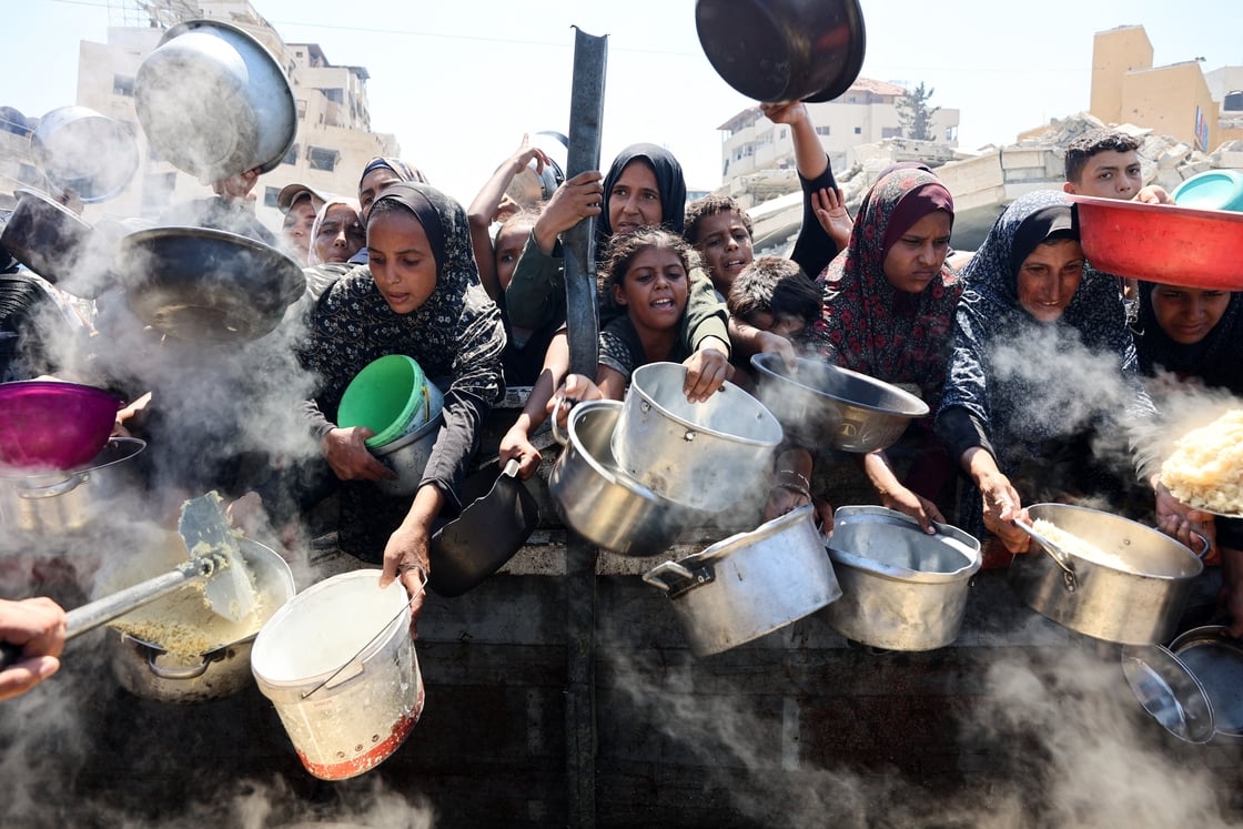 Palestinian women and girls jostle to receive cooked rice from a charity kitchen in Gaza City on 23 August