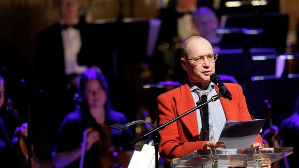 writer Quentin Fottrell, reading on stage with RTÉ Concert Orchestra in background, at Sunday Miscellany Christmas Concert, National Concert Hall, Dec 2025