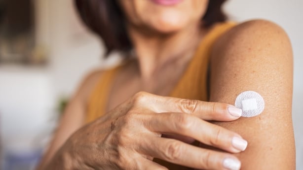 A woman in menopause sticks a transdermal patch on the skin. Hormone replacement therapy in menopause concept