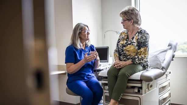 Female doctor in scrubs consulting with senior woman in exam room