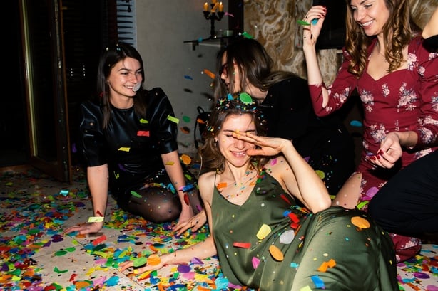 Group of beautiful young people throwing colorful confetti while dancing and looking happy. Friends making big party in the night. New year's or Birthday party. Series.