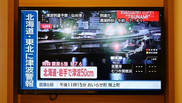 A tsunami warning flashes over live footage of a waterfront area, on a television screen in Sapporo
