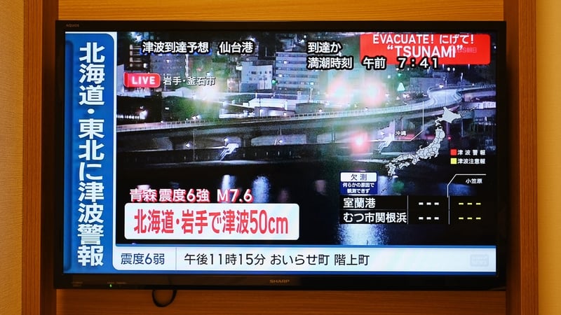 A tsunami warning flashes over live footage of a waterfront area, on a television screen in Sapporo, in northern Japan