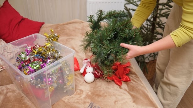 A woman tidying away Christmas decorations
