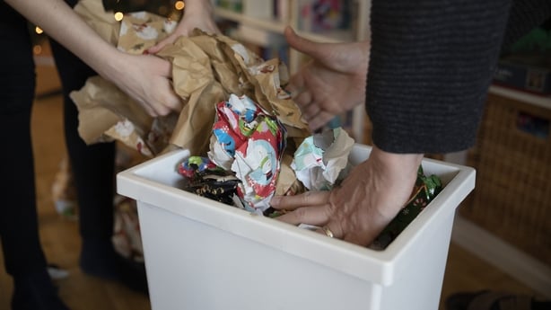 A couple cleaning away Christmas wrapping paper