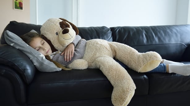 Girl relaxing on couch holding a large stuffed toy dog