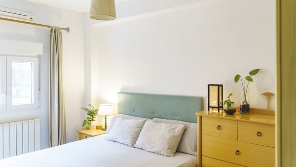 Pillows on an empty bed alongside a chest of drawers