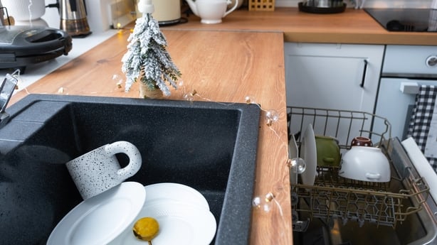 Dirty dishes in the sink in the garlanded kitchen, a holiday after a feast at Christmas. Mess after the guests for the New Year, kitchen cleaning, detergent, cleaning services