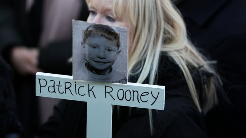 Patrick Rooney's sister Sharon holds a cross with his photo on it at a campaign march in 2018