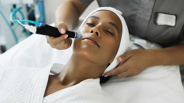 Young beautiful woman in the cosmetologist's office receives fractional mesotherapy for her face. Facial skin rejuvenation. Acne treatment. Moisturize face treatment. Hydrofacial. Hardware cosmetology. Beautician.