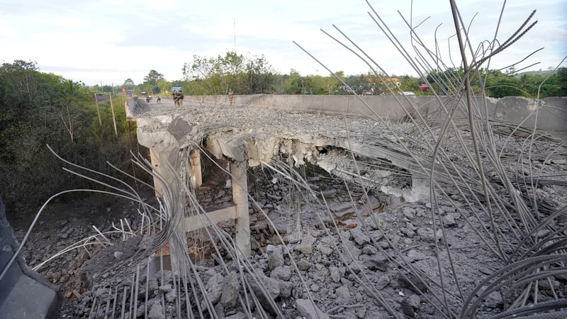 People stand on a damaged bridge in Pursat province in Cambodia