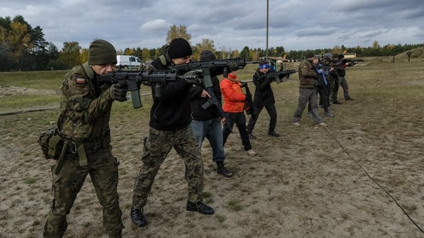 A Polish soldier shows civilians how to use a rifle during a military training day.