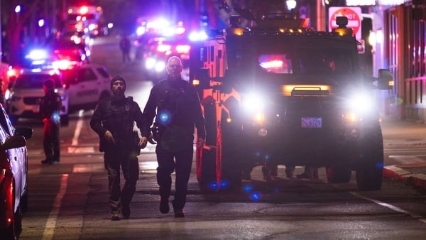 Police officers walk by a police vehicle at the scene of the shooting at Brown University’s campus.