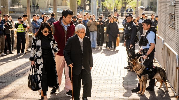 Jimmy Lai's wife, his son and the former bishop of Hong Kong, Cardinal Joseph Zen, walk towards the court which is guarded by police with dogs.
