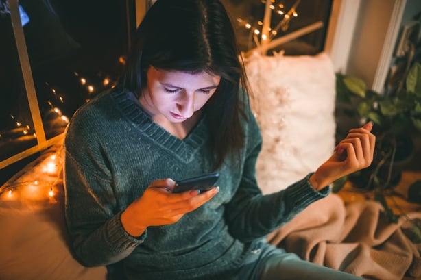Photo of a young woman chatting online and checking her social media on Christmas eve.