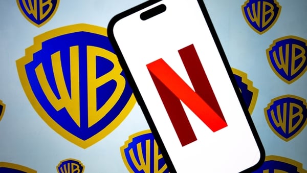 Netflix logo displayed on a mobile phone screen in front of the logo of Warner Bros