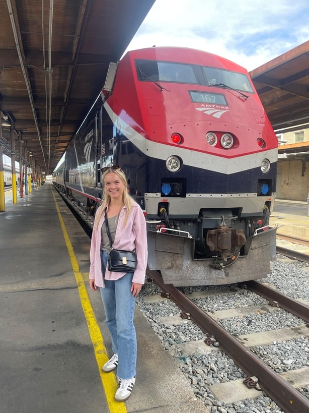 A woman standing in front of a train on the platform