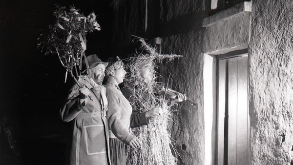 Black and white photograph of a strawboy and two wren boys outside the door at Lios Buí Kilnamartry Macroom Co Cork