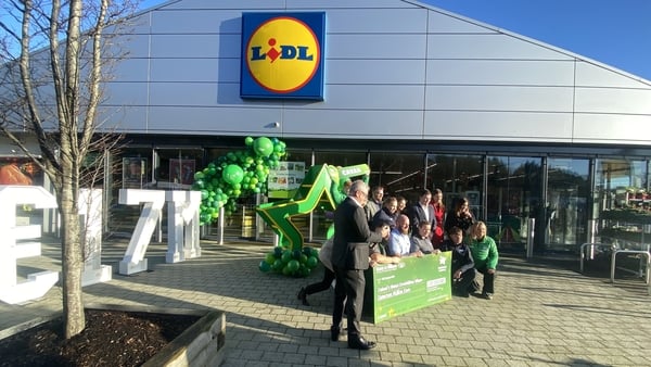 People gather in front of a lidl store holding a sign