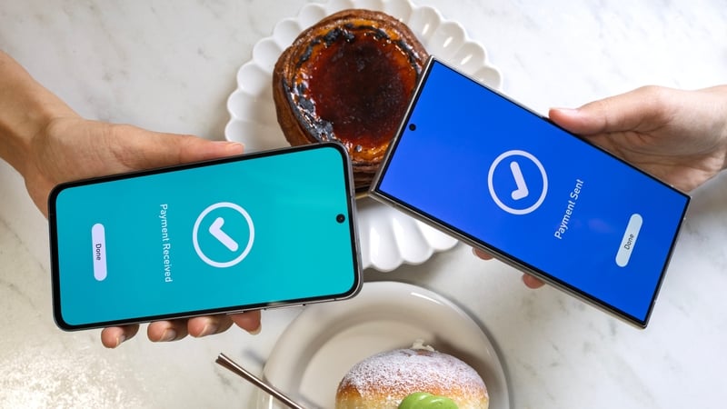 Close-up of two smartphones showing payment sent and payment received screens during a mobile transaction, with desserts and drinks in the background at a cafe.