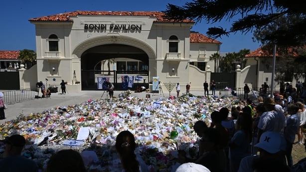 SYDNEY, AUSTRALIA - DECEMBER 17: People continue to gather at a flower memorial beside Bondi Pavilion on December 17, 2025 in Sydney, Australia. Life slowly returned to normal at Bondi Beach, as funerals for the victims of Sunday's mass shooting continued at a Synagogue in the famous Sydney suburb. 