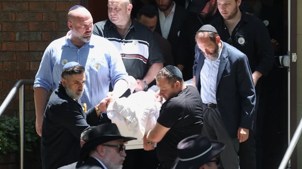Mourners carry a white coffin out of a synagogue 