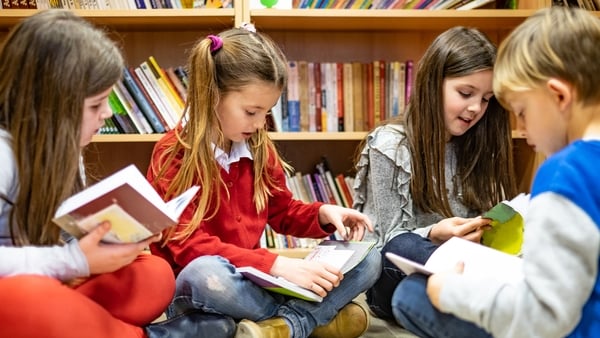 Group of children sitting on library floor and searcing a books