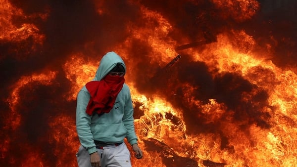 A protester walks next to burning tyres on a square near the European Parliament, as farmers protest against the EU-Mercosur free-trade deal between the European Union and the South American countries of Mercosur