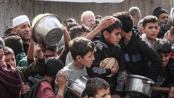DEIR AL-BALAH, GAZA - DECEMBER 6: Displaced Palestinians receive food and bread, distributed by a charity organization as people struggle with hunger due to limited number of humanitarian aid entries in Nuseirat Refugee Camp of Deir al-Balah, Gaza on Dece