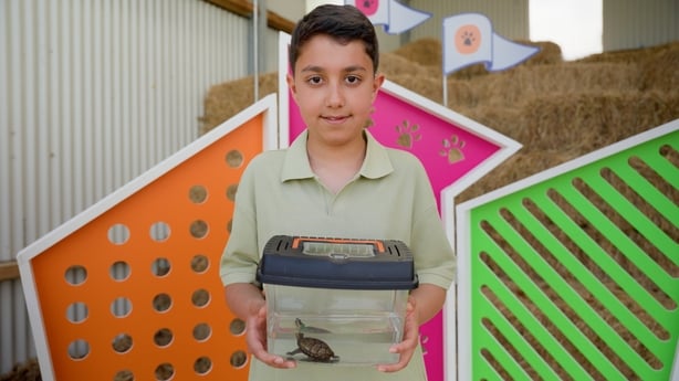 young boy holds an aquarium with a turrle inside.
